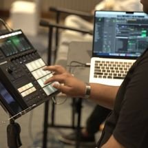Drummer mid-performance behind drum kit, arms raised, intense and energetic mood, stage lights and instruments visible