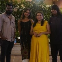 Band members standing together backstage, relaxed and smiling, casual environment with musical equipment in background