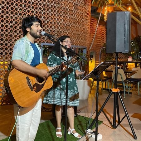 Guitarist playing electric guitar on stage, focused expression, surrounded by stage equipment and blue lighting, concert setting